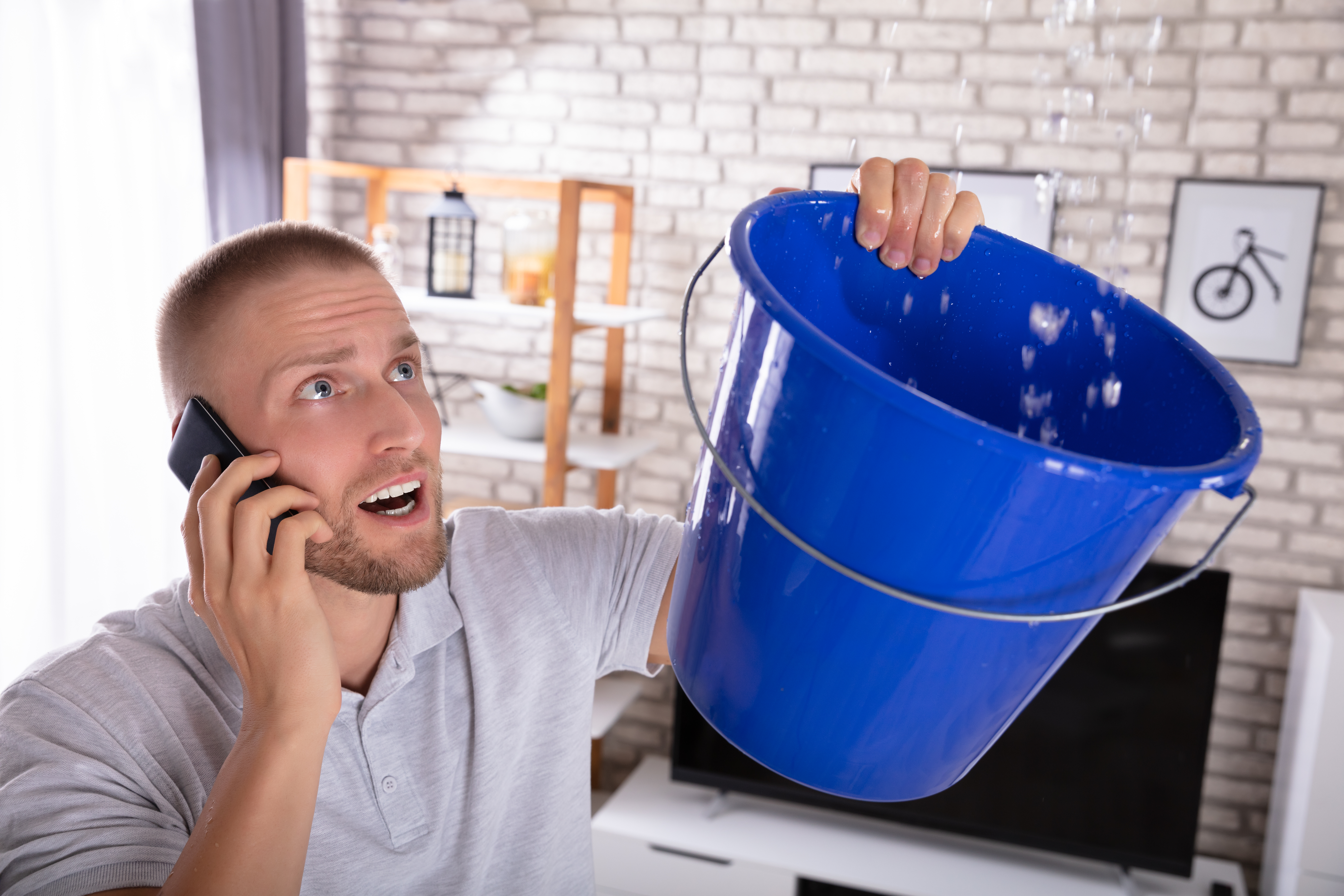 Homeowner calling for emergency water removal while catching ceiling leak